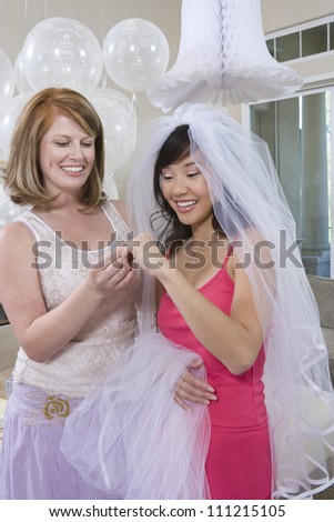 Happy young bride with her friend looking at engagement ring