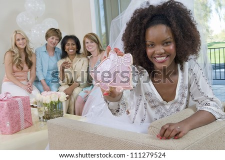 Portrait of an African American bride holding wedding bell with friends in the background