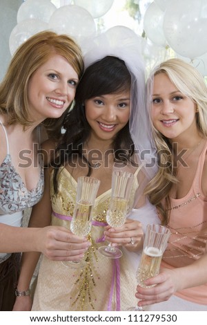 Portrait of happy three female friends holding champagne flute
