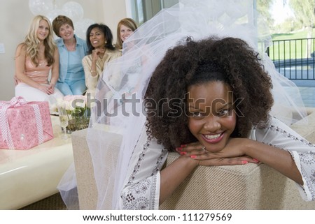 Young bride lost in thoughts with friends in the background