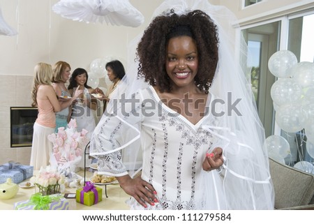 Portrait of an African American bride with friends in the background at party