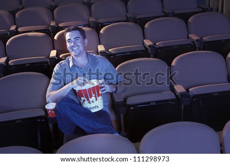 Man in theater watching movie with popcorn