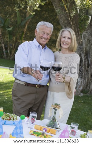 Portrait of happy senior couple standing together while toasting wine