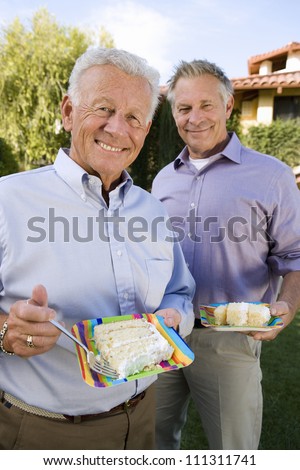 Portrait of senior male friends eating cake