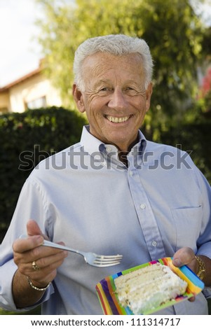 Portrait of happy senior man eating piece of cake at party