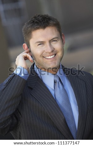 Happy businessman with earphone looking away