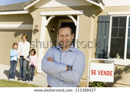 Portrait of happy middle aged man with family standing in front of new house