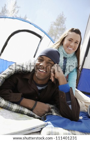 Portrait of a happy couple relaxing on a camping trip in front of the camping tent