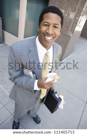 High angle view of happy African American business man eating sandwich