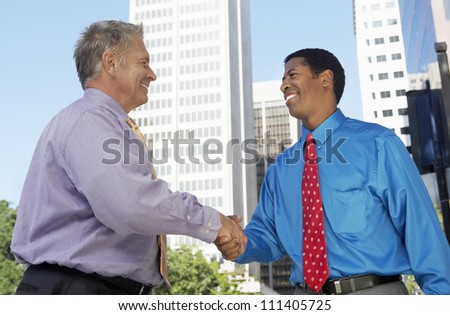 Two happy successful businessmen shaking hands for a deal