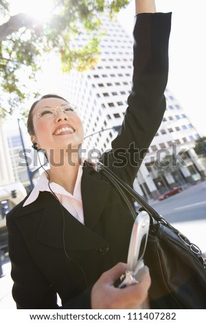Portrait of happy business woman waving hand with building in the background