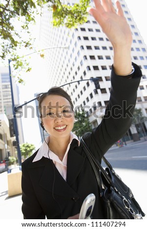 Portrait of happy business woman waving hand on street