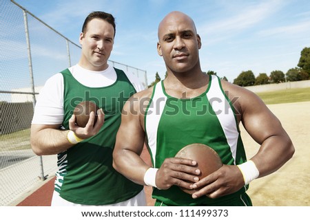 Portrait of shot putters holding shot put and discus on track