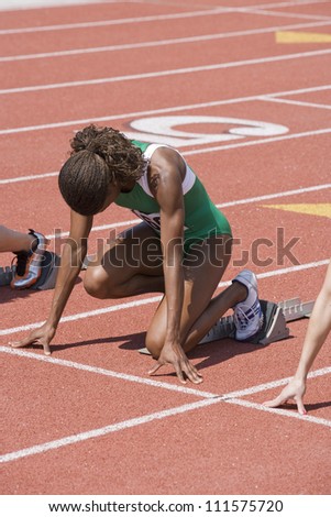 African American Female athlete with competitors at starting line