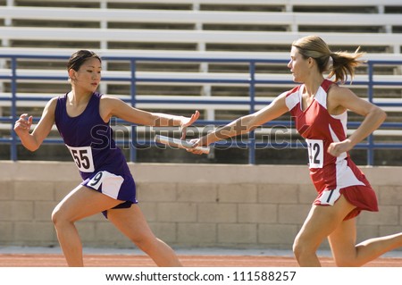 Female runners passing baton in relay race