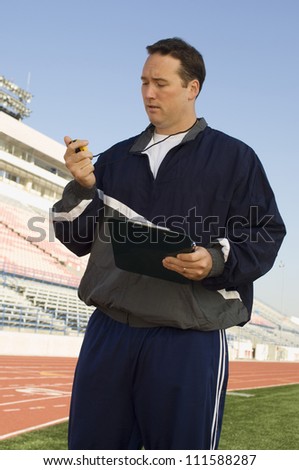 Male instructor with clipboard looking at stopwatch
