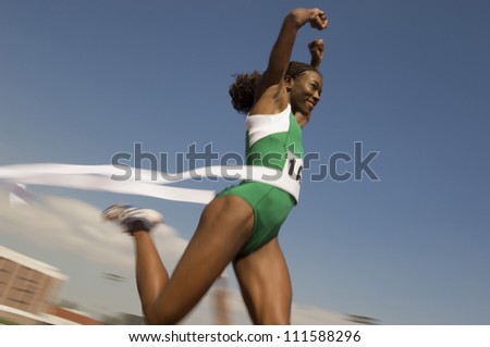 African American female athlete crossing finish line in race