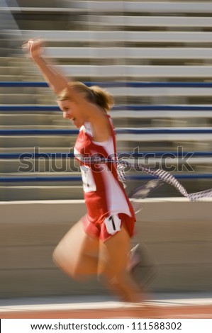 Blurred motion of excited female athlete runner crossing the finishing line