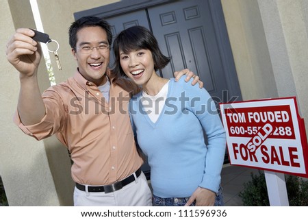Portrait of happy man with woman holding keys of their new home