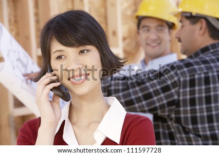 Woman on call with contractors working in background at construction site