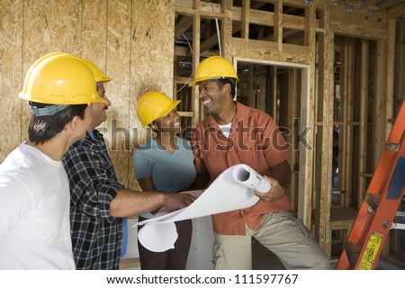 African American couple with blueprint at construction site