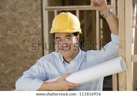 Asian construction worker holding blueprints