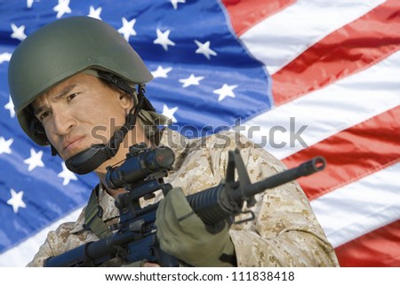 Soldier with assault rifle in front of US flag