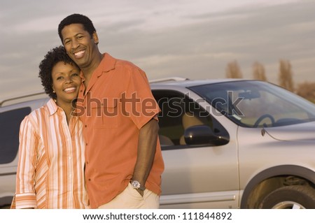 Happy African American couple standing in front a car