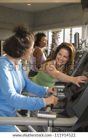 Women helping each other riding an exercise bike