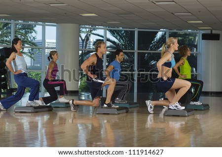Six people exercising on step in aerobics class