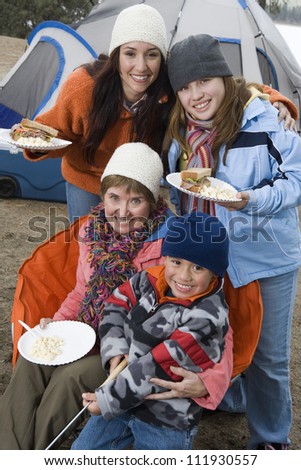 Happy family having food at campfire