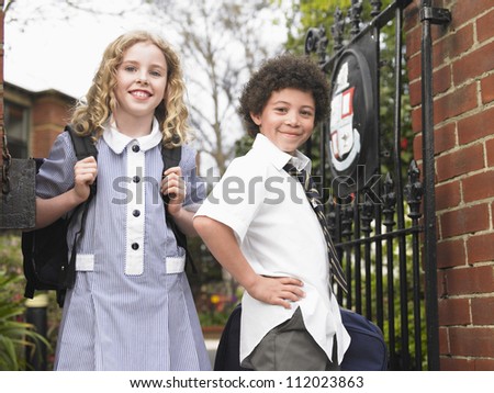 Two friends standing in front of gate of the school
