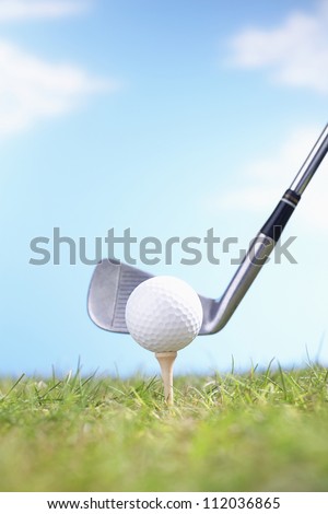 Golf ball on tee with driver ready to tee off