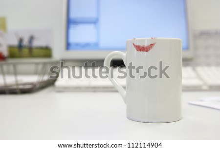 Lipstick print on coffee mug on computer desk