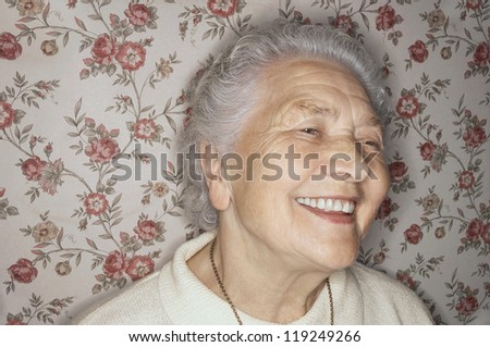 Happy senior lady looking away with wallpaper in the background