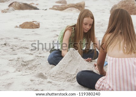 Sisters making sand castle on beach