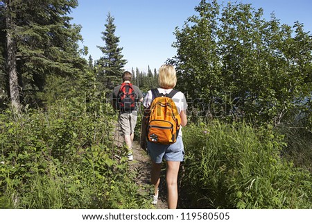 Rear view of a couple with backpack walking along forest trail
