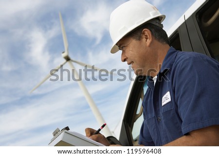 Close up of a male architect writing on clipboard at wind farms