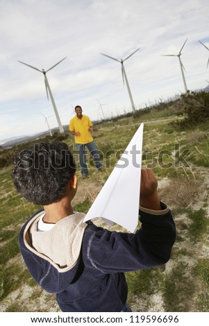 An African American father and son playing with paper plane at wind farm