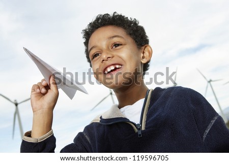 Cute little boy playing with paper plane at wind farm