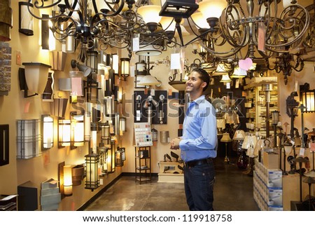 Happy young man browsing for lights fixture in store