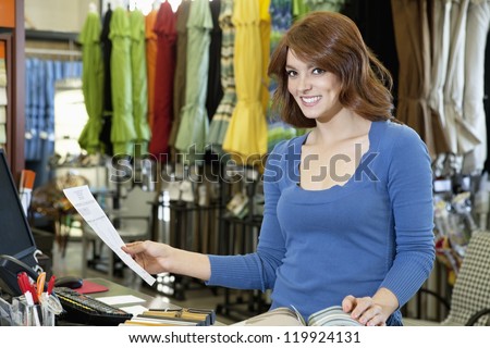 Portrait of beautiful young woman with paper and textile samples standing in store