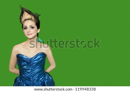 Portrait of spiked hair young woman with hands behind back over green background