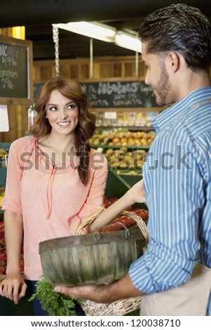 Happy young woman looking at store clerk in supermarket
