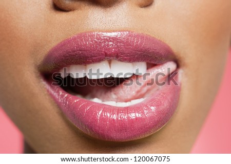 Cropped image of woman licking pink lipstick