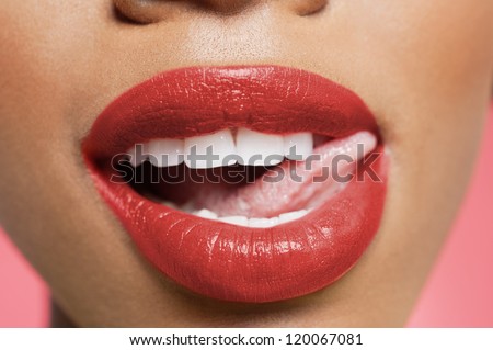 Cropped image of woman licking red lipstick
