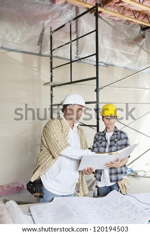 Construction team looking at paper with blueprints on table