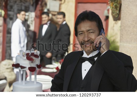Portrait of a middle aged man using cell phone with men in the background