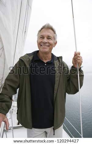 Happy middle aged man holding rope on sail boat
