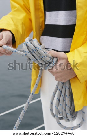 Midsection of a man holding rope on sail boat